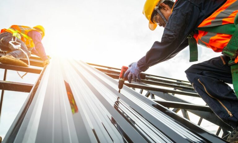 workers installing stainless steel panel for Houston metal building construction